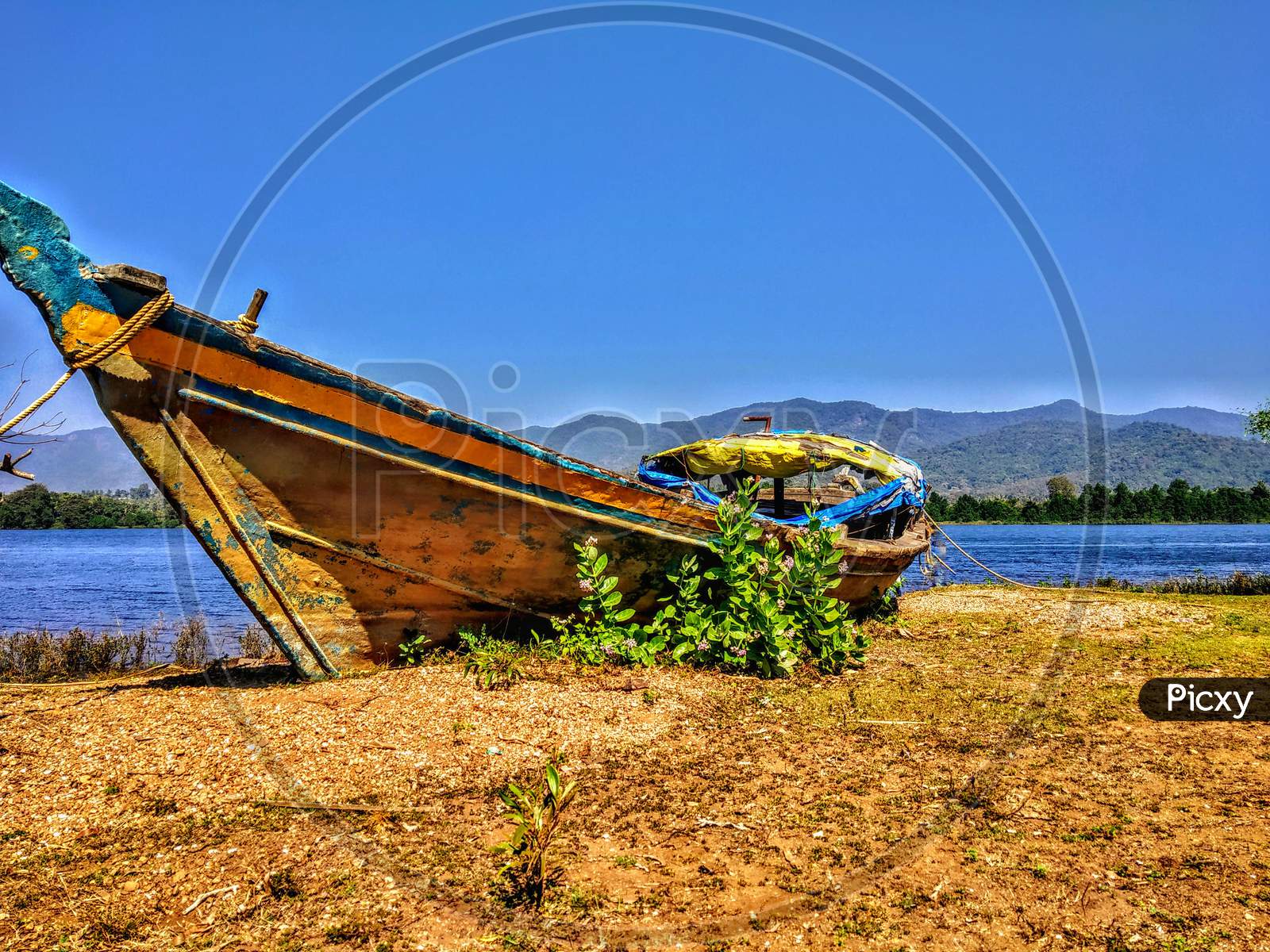 A Old Boat Parked Beside The River With Mountains At Other Side In Western Ghats.