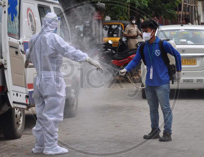 A health worker sprays disinfectant on another health worker outside a Covid-19 test collection center outside a hospital in Guwahati, Assam on July 06, 2020.