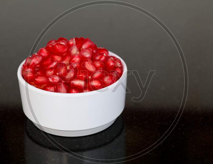 Fresh Red Color Pomegranate Kernels In A White Bowl