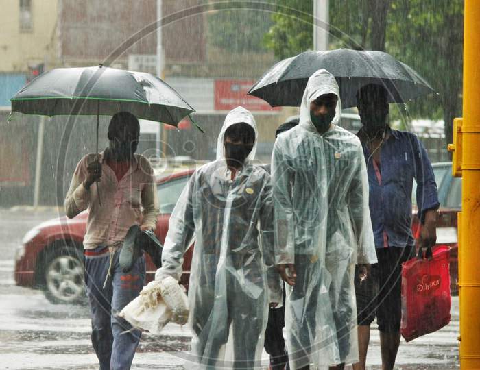 People walk on the road during heavy rains, in Mumbai on July 4, 2020.
