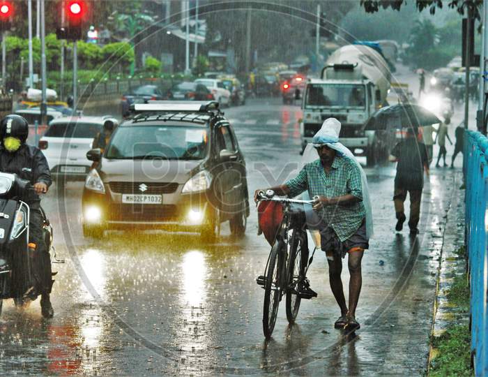 A man walks with his cycle during heavy rains, in Mumbai on July 4, 2020.