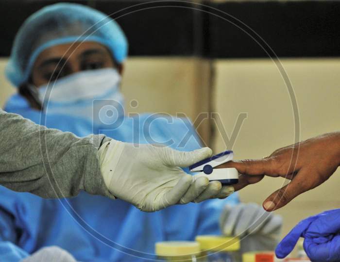 A healthcare worker checks the pulse of a resident during a medical campaign for the coronavirus disease (COVID-19), in Mumbai, India, July 1, 2020