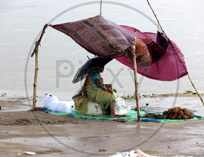 A woman vendor sits under a makeshift tent with an umbrella to escape the heavy downpour in Prayagraj, Uttar Pradesh on July 06, 2020