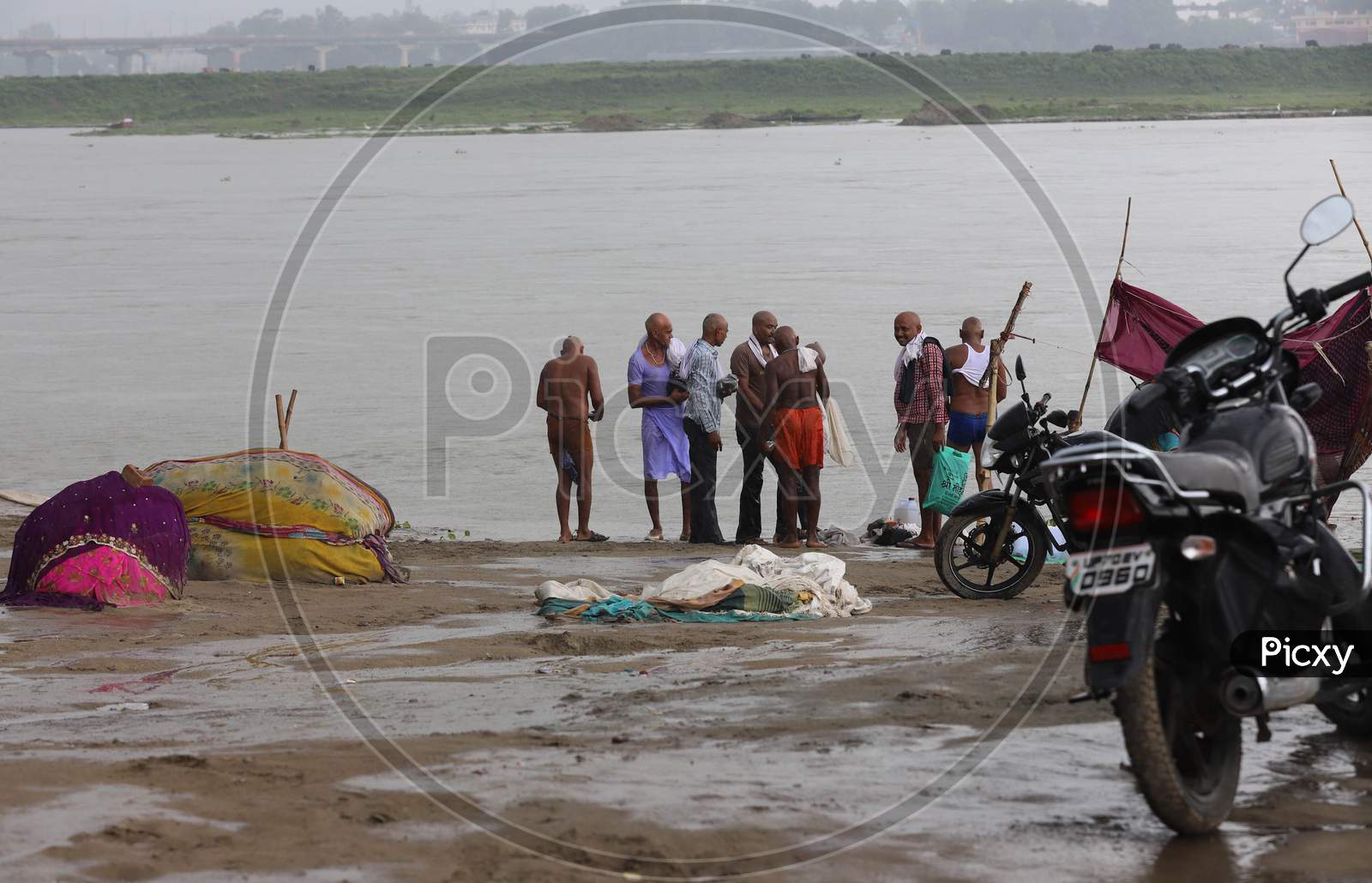 People walking under a heavy downpour on the banks of River Ganga in Prayagraj, Uttar Pradesh on July 6, 2020