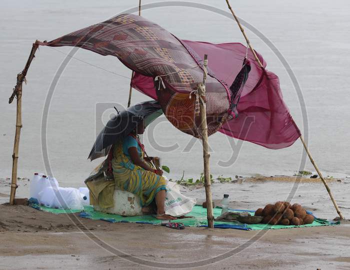 A woman vendor sits under a makeshift tent with an umbrella to escape the heavy downpour in Prayagraj, Uttar Pradesh on July 06, 2020