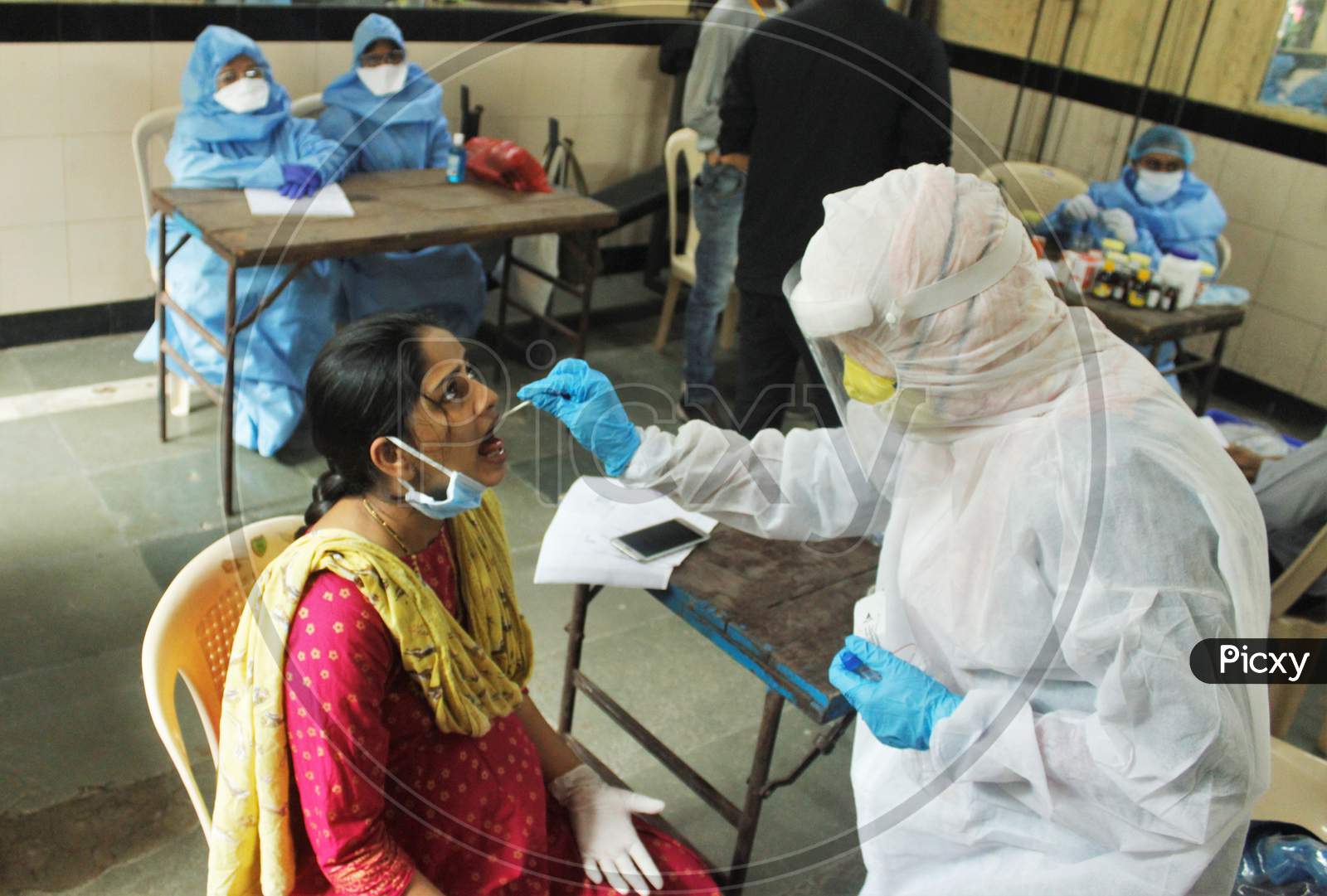 A healthcare worker wearing personal protective equipment (PPE) collects a swab sample from a pregnant woman, during a check-up campaign for the coronavirus disease (COVID-19), in Mumbai, India on July 1, 2020.