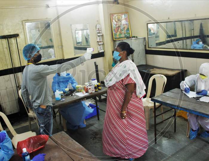 A healthcare worker checks the temperature of a resident during a medical campaign for the coronavirus disease (COVID-19), in Mumbai, India, July 1, 2020.