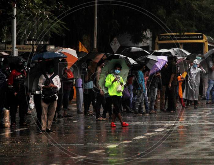 People wait to board a public bus during heavy rains, in Mumbai, India on July 4, 2020.