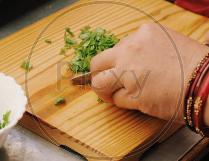 Woman Cutting Coriander leaves on chopping board