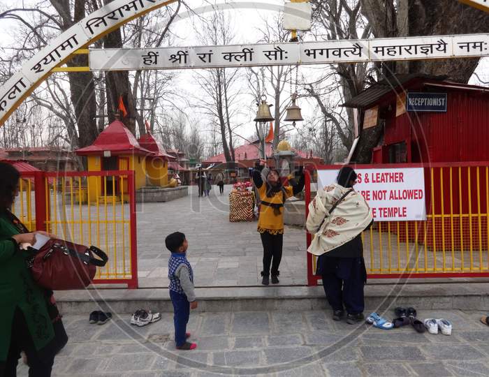 baby girl jumping up in effort to ring the bell in Ksheer Bhawani Temple