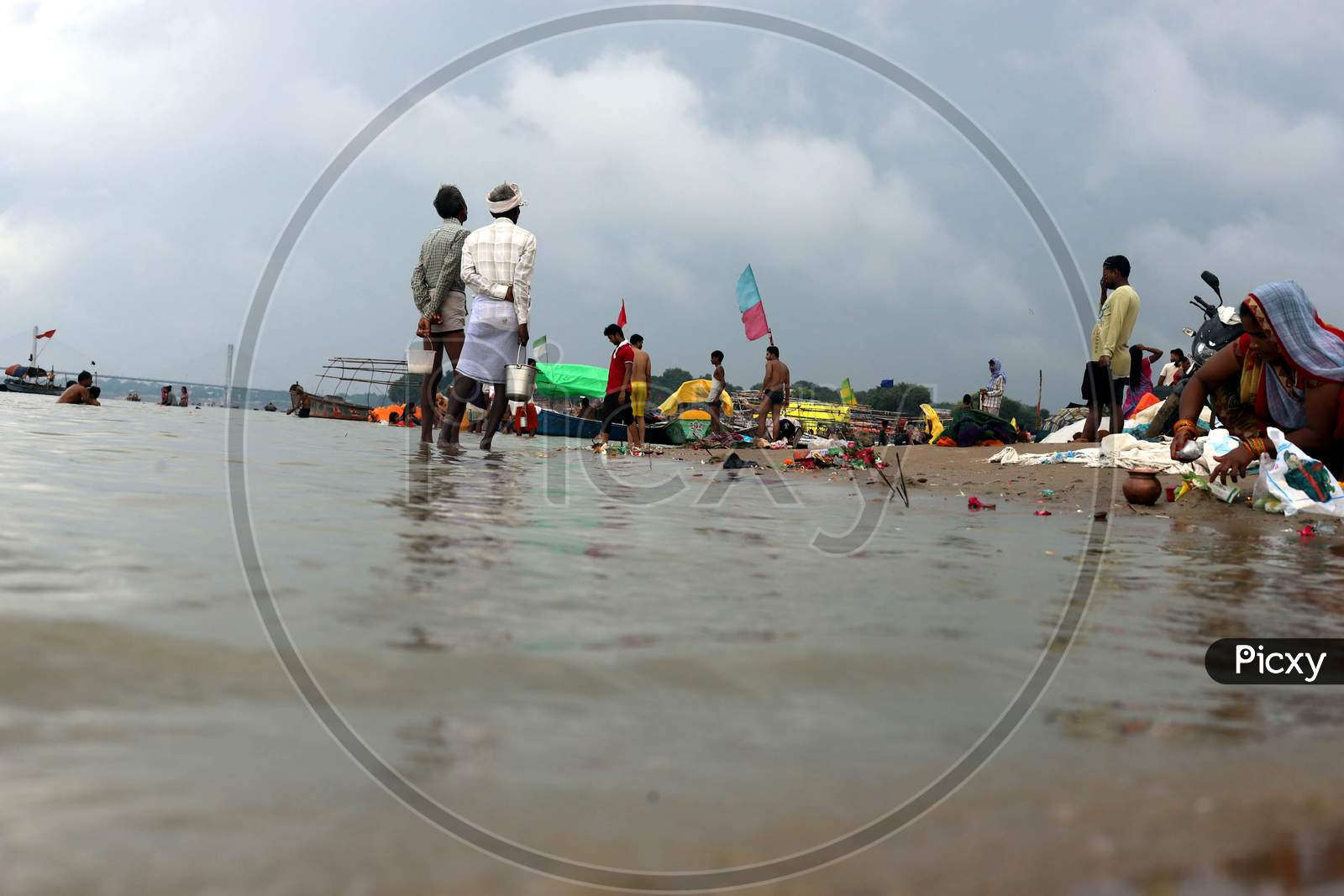 People stand ashore of River Ganga which witnessed an increase in its water level due to heavy rainfall in Prayagraj, Uttar Pradesh on July 07, 2020