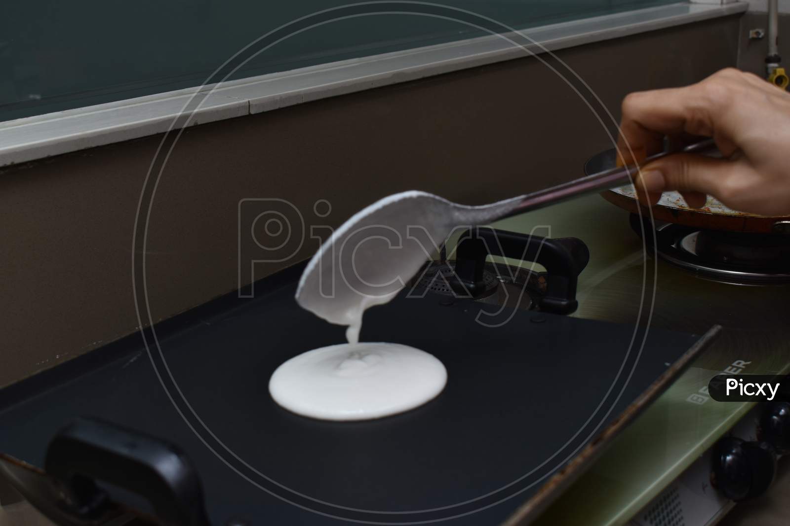 Pouring White Dosa Batter On Hot Non Stick Pan With Spoon