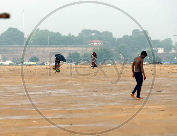 People walk on the shores of river Ganga under a heavy downpour in Prayagraj,Uttar Pradesh on July 07,2020