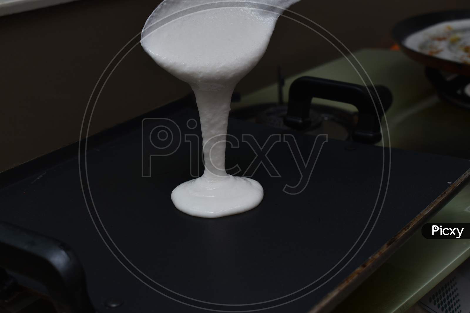 Pouring White Dosa Batter On Hot Non Stick Pan Or Tawa With Spoon