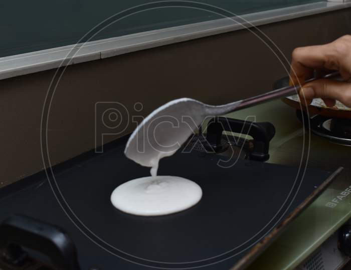 Pouring White Dosa Batter On Hot Non Stick Pan With Spoon