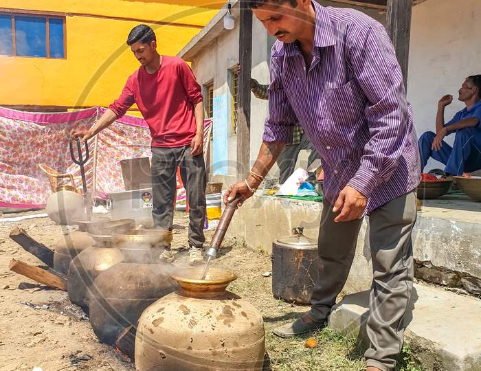 Mandi, Himachal Pradesh/India - June 15 2020: Portrait of people making Indian food in marriage in big pot in outdoor during lockdown days with selective focus, selective focus on subject, background