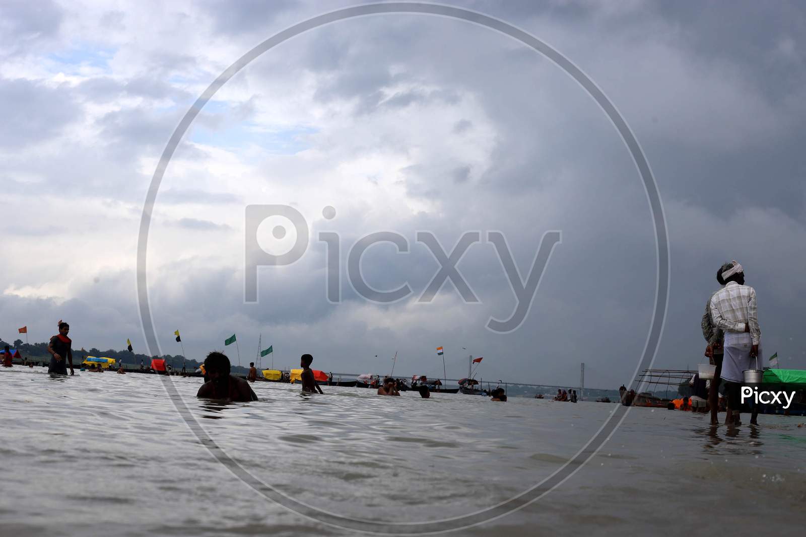 People take a dip in River Ganga which saw an increase in its water level due to heavy rainfall in Prayagraj, Uttar Pradesh on July 07, 2020