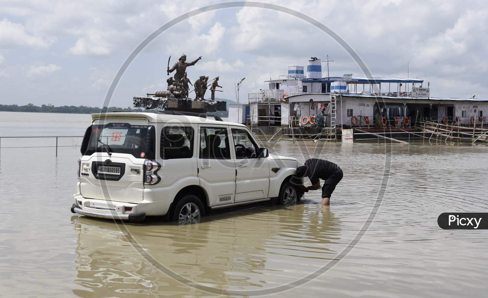 A man washing his car using flood water
