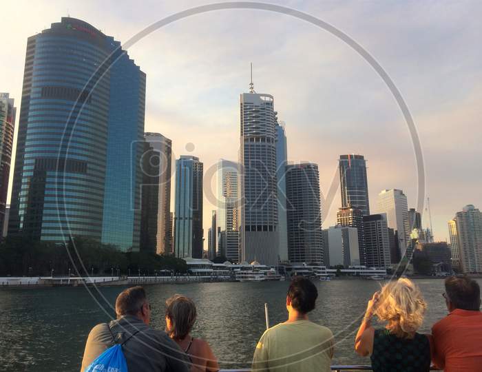 People On Brisbane'S Citycat Ferry With The City Skyline In The Background