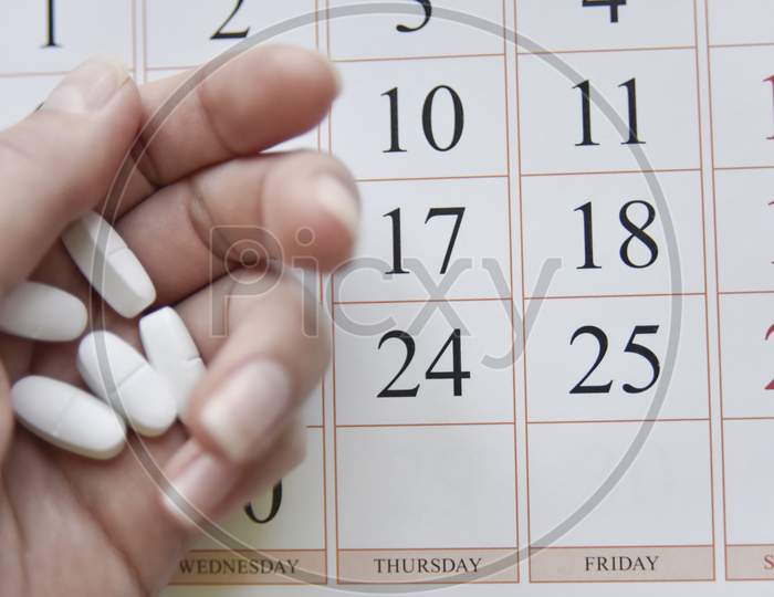 Selective Focus At Pills And Calendar With Blurry Hand