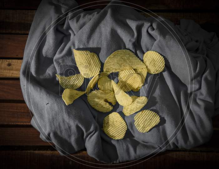 Crispy potato chips in bowl on dark table