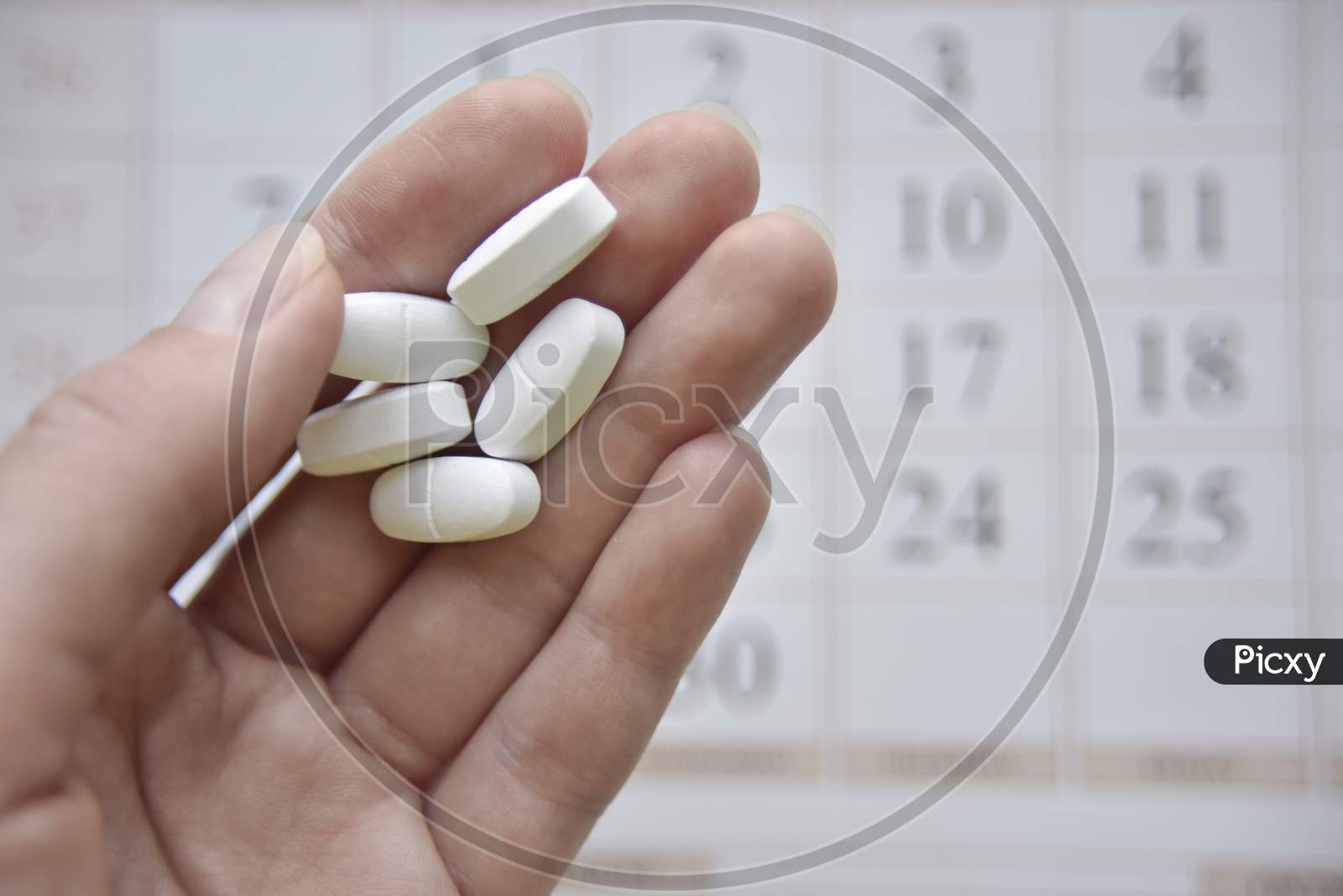 Selective Focus At The Hand And Pills With The Blurred Calendar At The Background