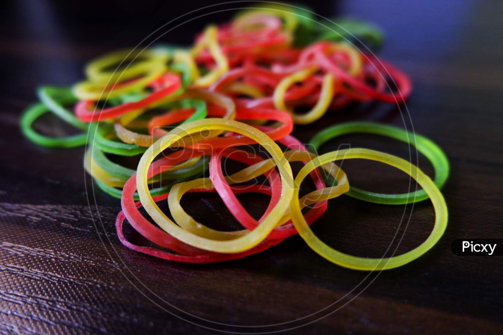 Closeup Shot Of Colorful Rubber Bands Isolated On Brown Wooden Table