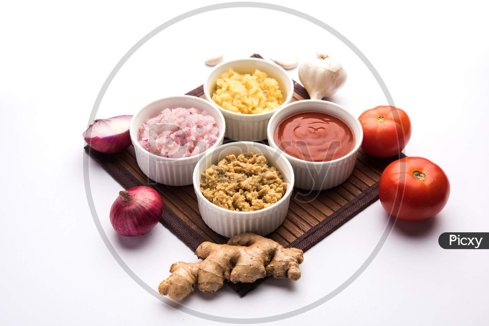 Ginger, Garlic, onion and tomato paste and powder in and raw form. Group of Basic Indian food ingredients over wooden background