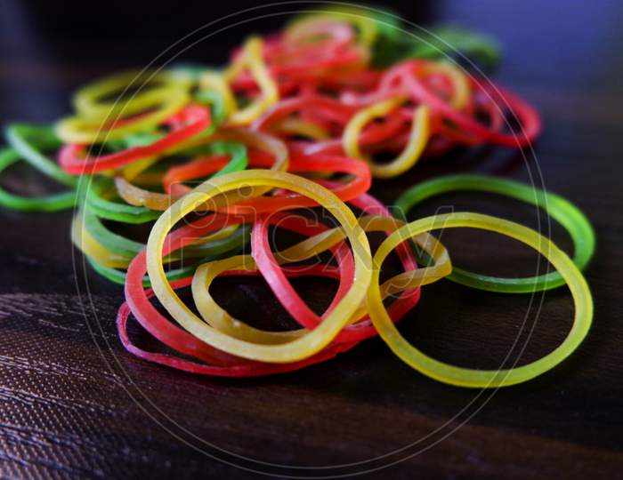 Closeup Shot Of Colorful Rubber Bands Isolated On Brown Wooden Table