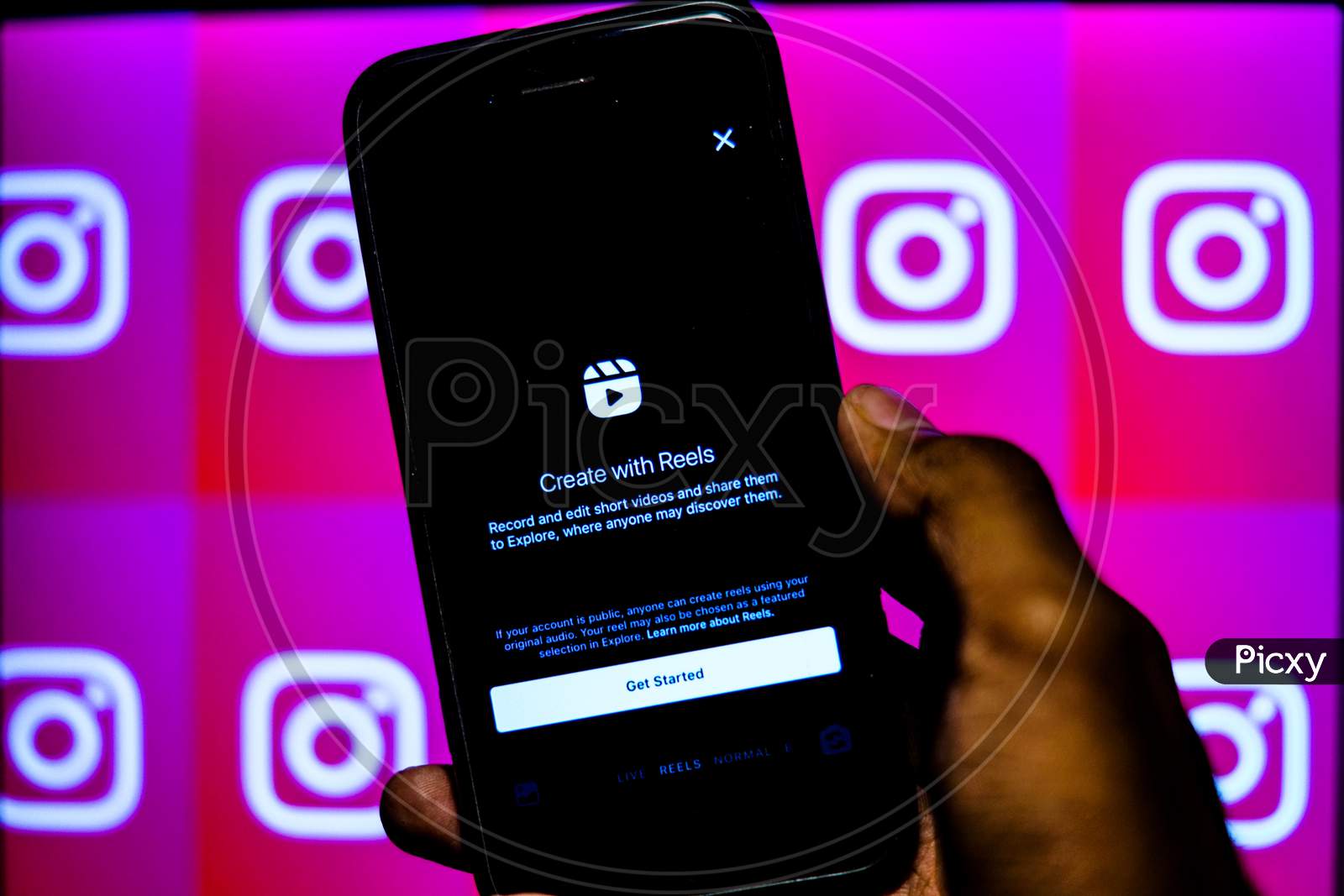 Instagram new update Instagram Reels on a Mobile Screen with a finger about to touch and Instagram logo in the background