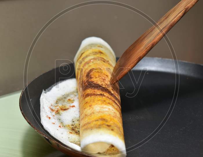 Rolling The Dosa On Hot Non Stick Tawa Pan With Wooden Spatula
