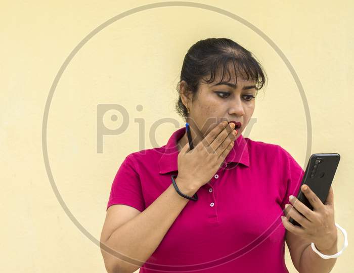 Indian Female Model Looking At Mobile Phone Surprise Face In Yellow Background With Copy Space For Text