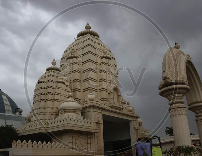 A Hindu Temple Located In Mathura Against Dramatic Black Cloud