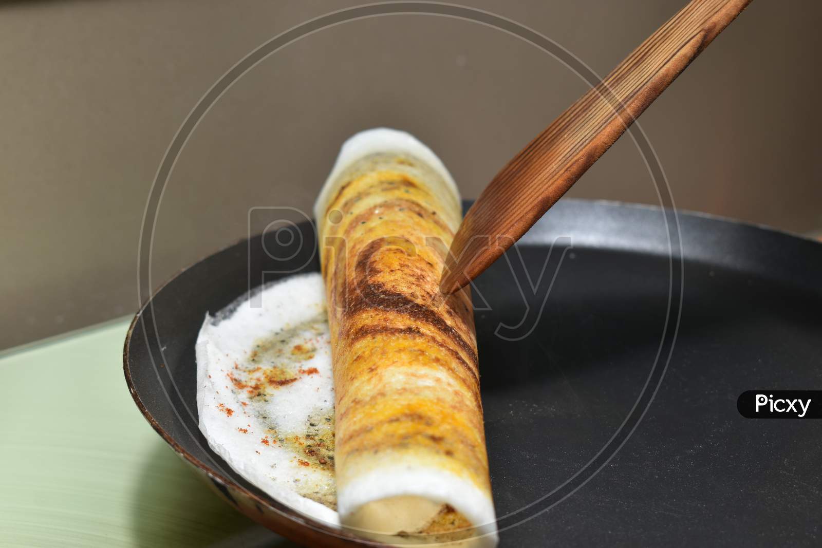 Rolling The Dosa On Hot Non Stick Tawa Pan With Wooden Spatula