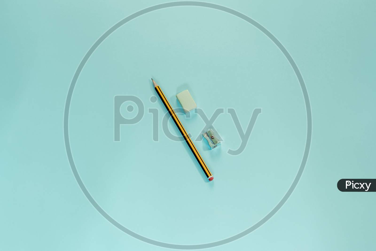 A Pencil, A Eraser And A Pencil Sharpener Over A Blue Pastel Wallpaper