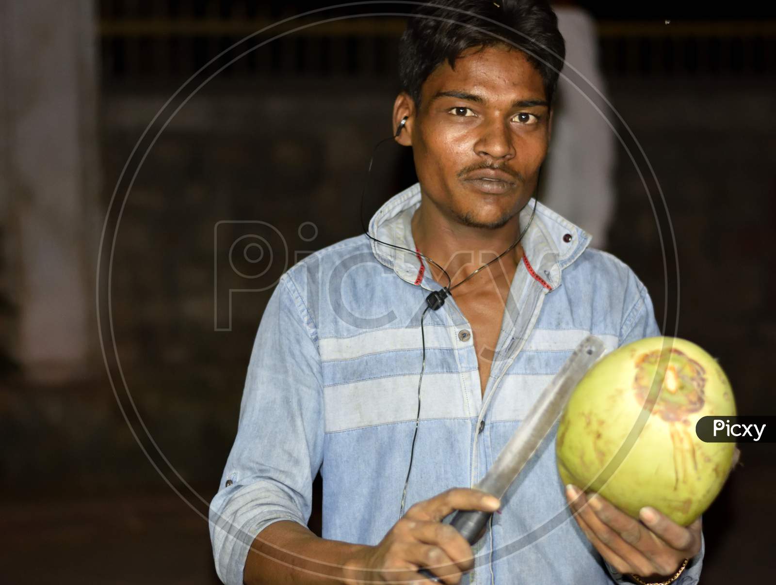 A Local Green Coconut Seller Posing And Cutting A Coconut To Expose The Water