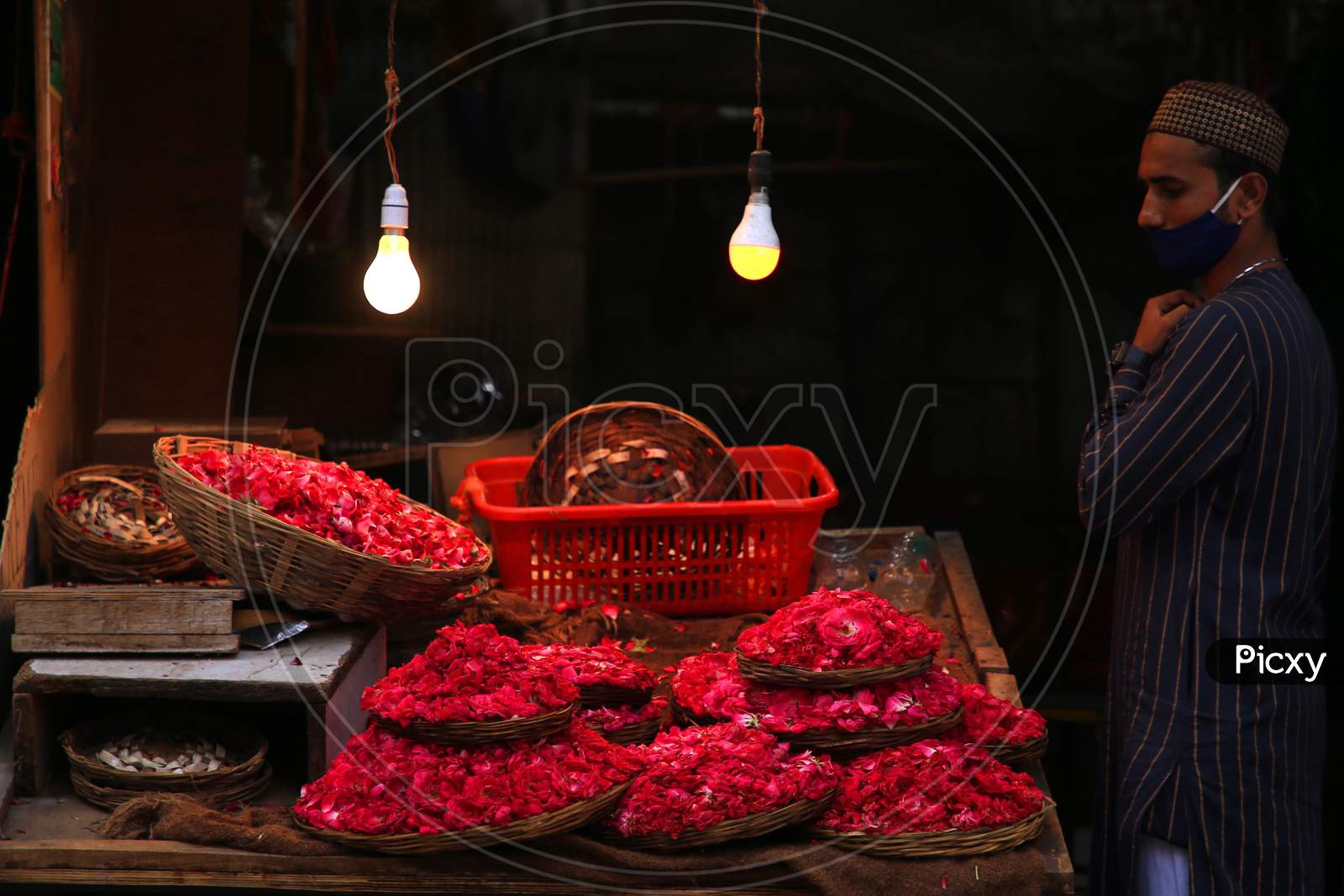 A Muslim devotee stands next to a stall selling flower petals outside the shrine of Sufi saint Khwaja Moinuddin Chishti In Ajmer, On August 1, 2020.