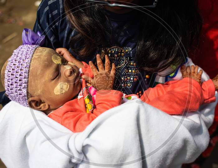 A Rohingya refugee girl holds an infant child painted with traditional Myanmar make up during Eid-Al-Adha (Feast of Sacrifice) festival at a camp in the outskirts of New Delhi, India on August 1, 2020.