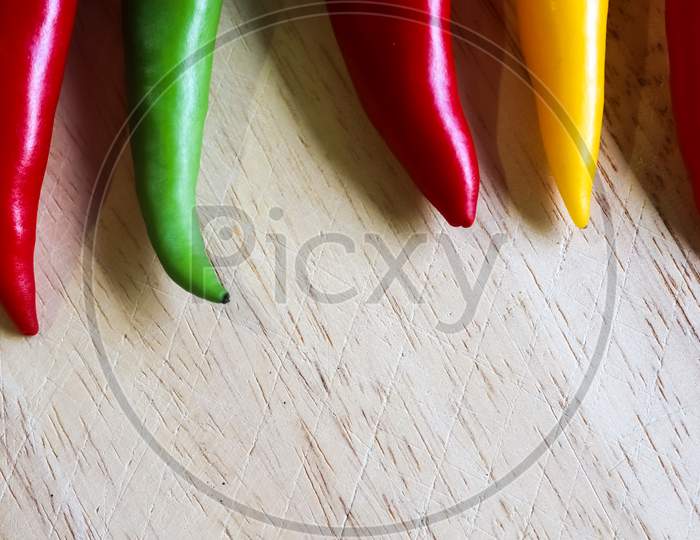 Top and perspective view of chili pepper and steel knife on a wooden cutting board with an isolated background