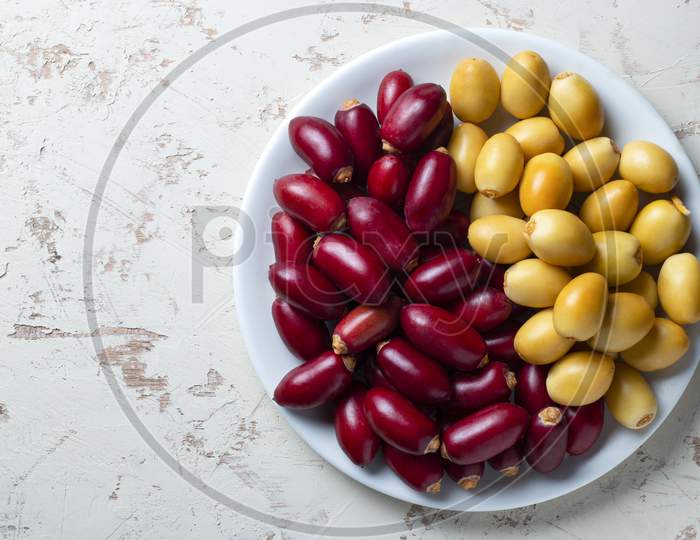 Red And Yellow Fresh Dates Fruit In White Plate
