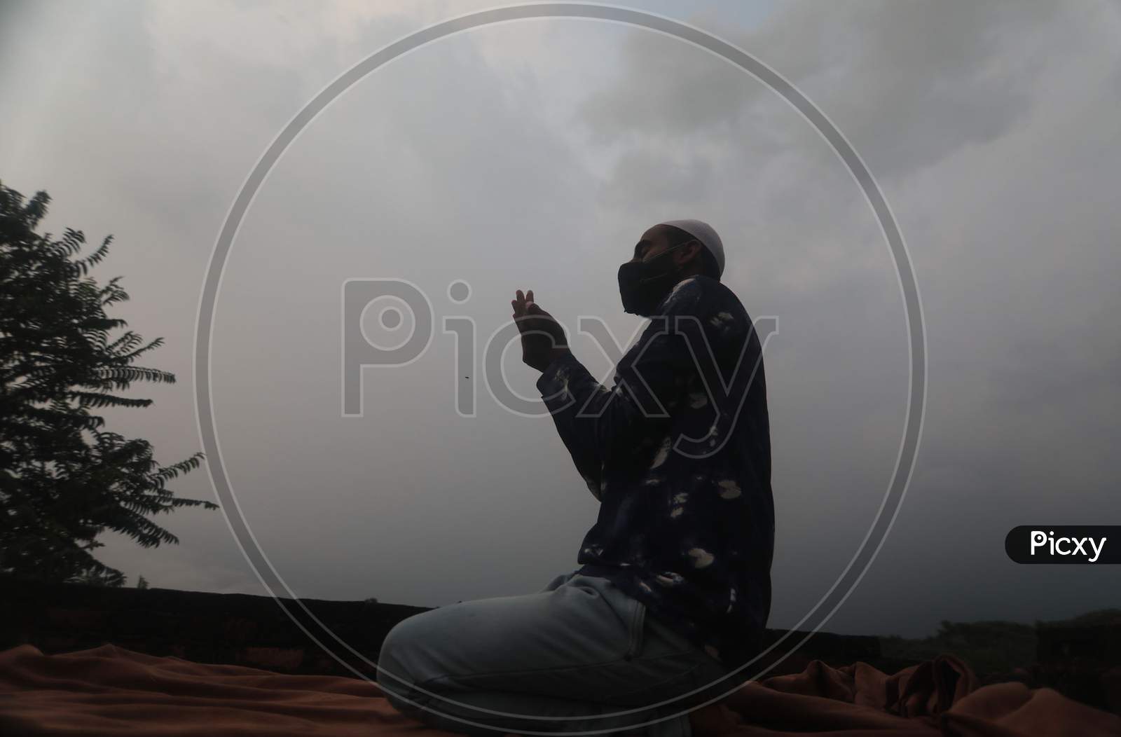 A man offers prayers at a roof of a house during Eid al-Adha festival as authorities imposed weekend lockdown in Jammu on August 1, 2020.