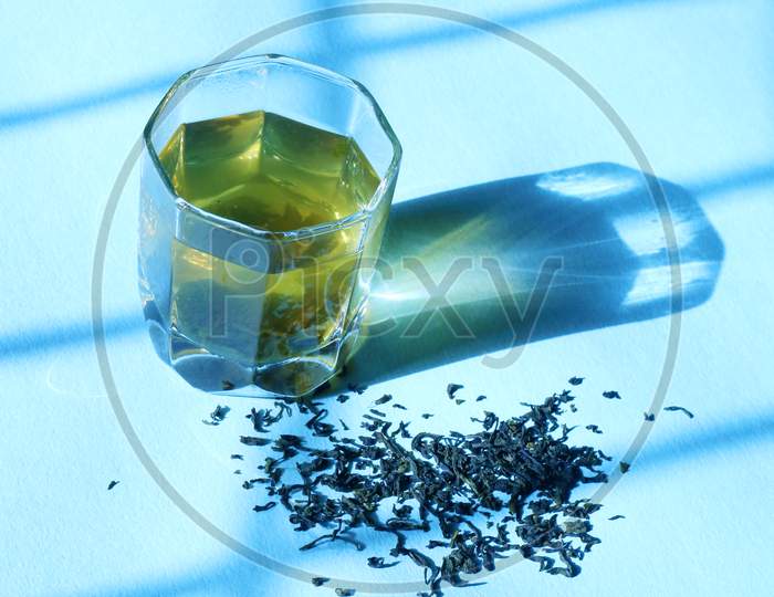 Green Tea In A Glass With Morning Sun Rays On Blue Isolated Background