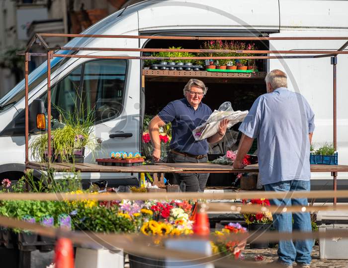 An Outdoor Flower Market Stall Owner Serving A Customer