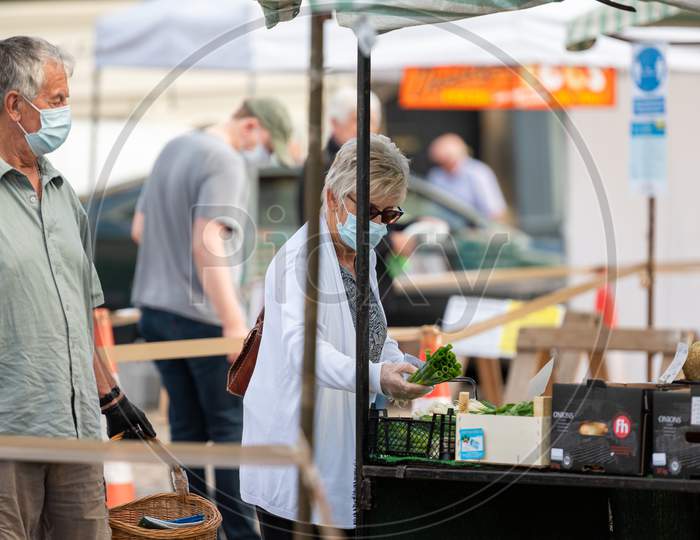 A Mature Woman Wearing A Protective Face Mask Shopping At An Outdoor Fruit And Veg Market Stall