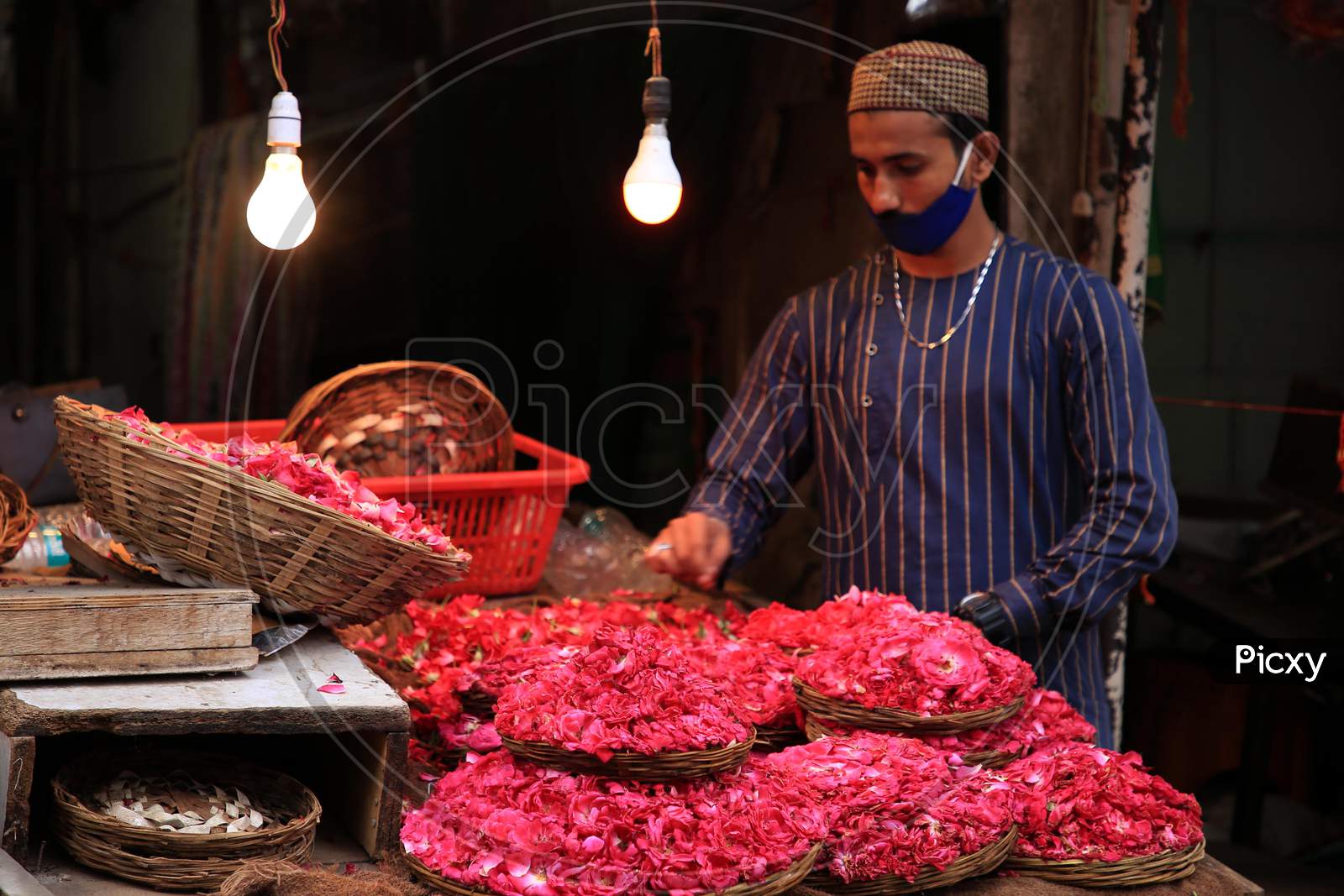 A Muslim devotee stands next to a stall selling flower petals outside the shrine of Sufi saint Khwaja Moinuddin Chishti In Ajmer, On August 1, 2020.