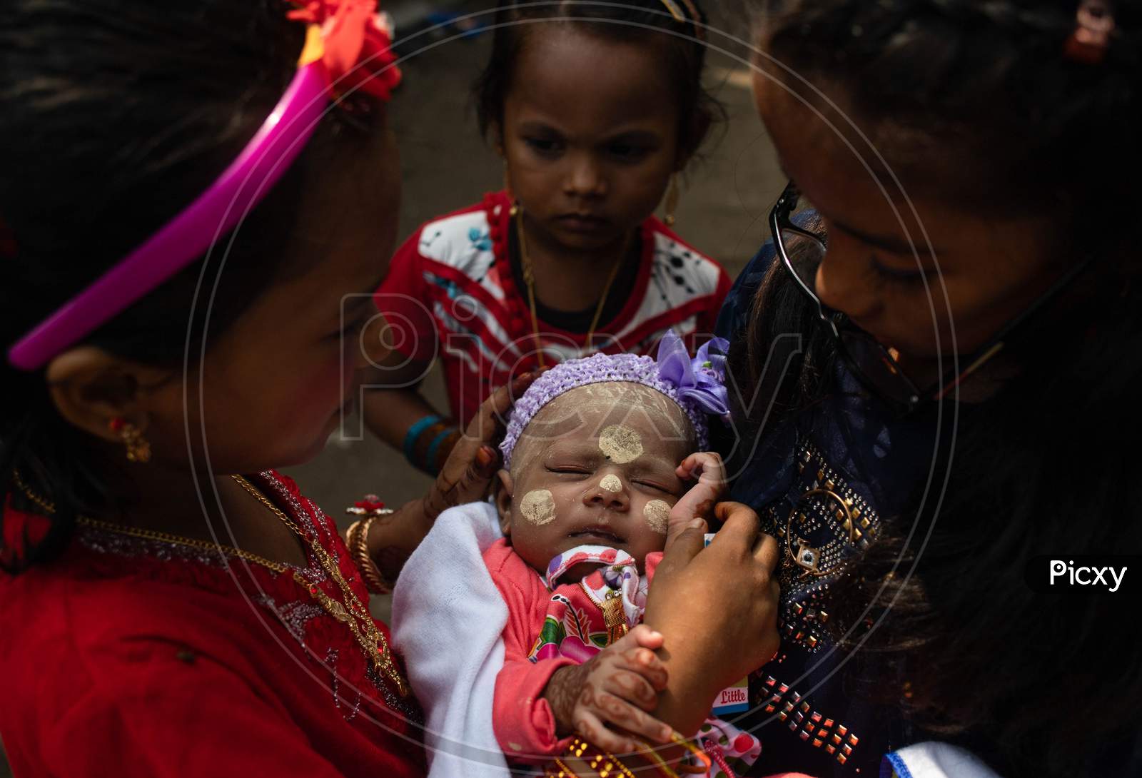 Rohingya refugee girls hold an infant child painted with traditional Myanmar make up during Eid-Al-Adha (Feast of Sacrifice) festival at a camp in the outskirts of New Delhi, India on August 1, 2020.