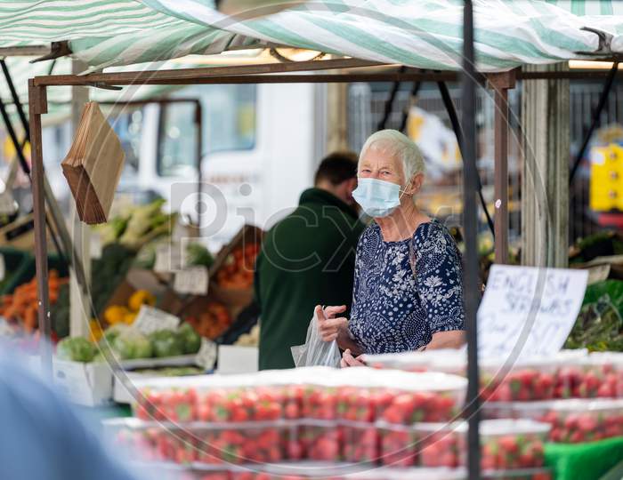 A Mature Female Customer Wearing A Protective Face Mask At An Outdoor Market