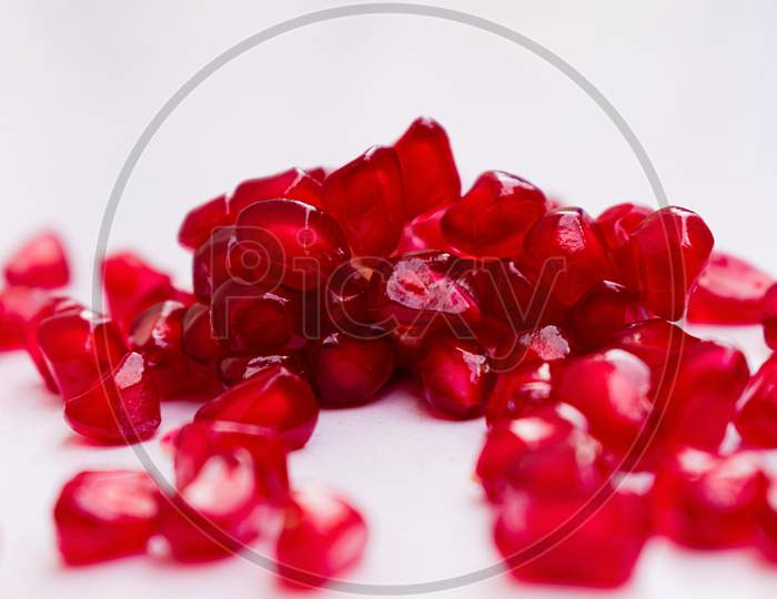 Collection of fresh pomegranate seeds having shallow depth of field isolated on white.