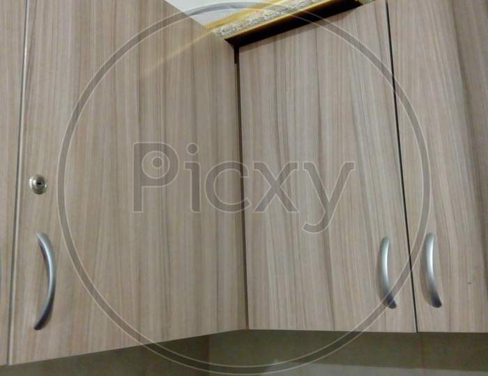 Laminate Finished Over Head Storage Cabinet With Stainless Steel Make Handle And Lock For An Kitchen Or Pantry Of An Residential Flat Or Office