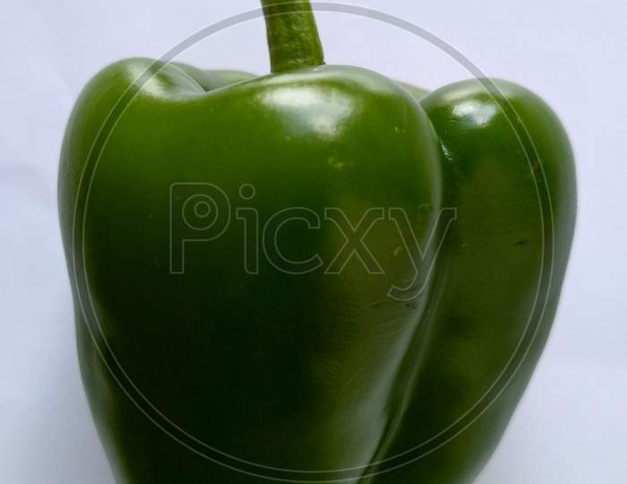 Green capsicum isolated on off-white background.